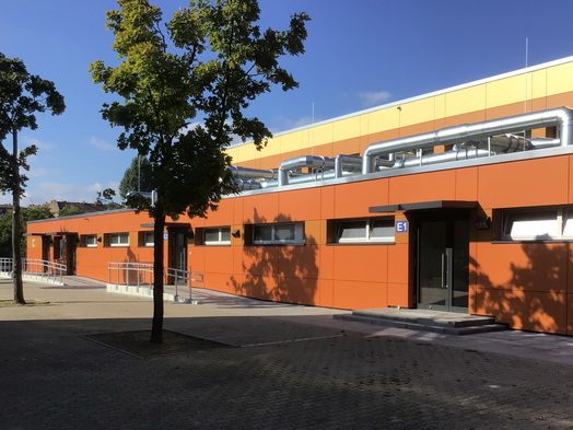 Sanierte Sporthalle der Hans-Fallada-Schule mit orangefarbener Fassade